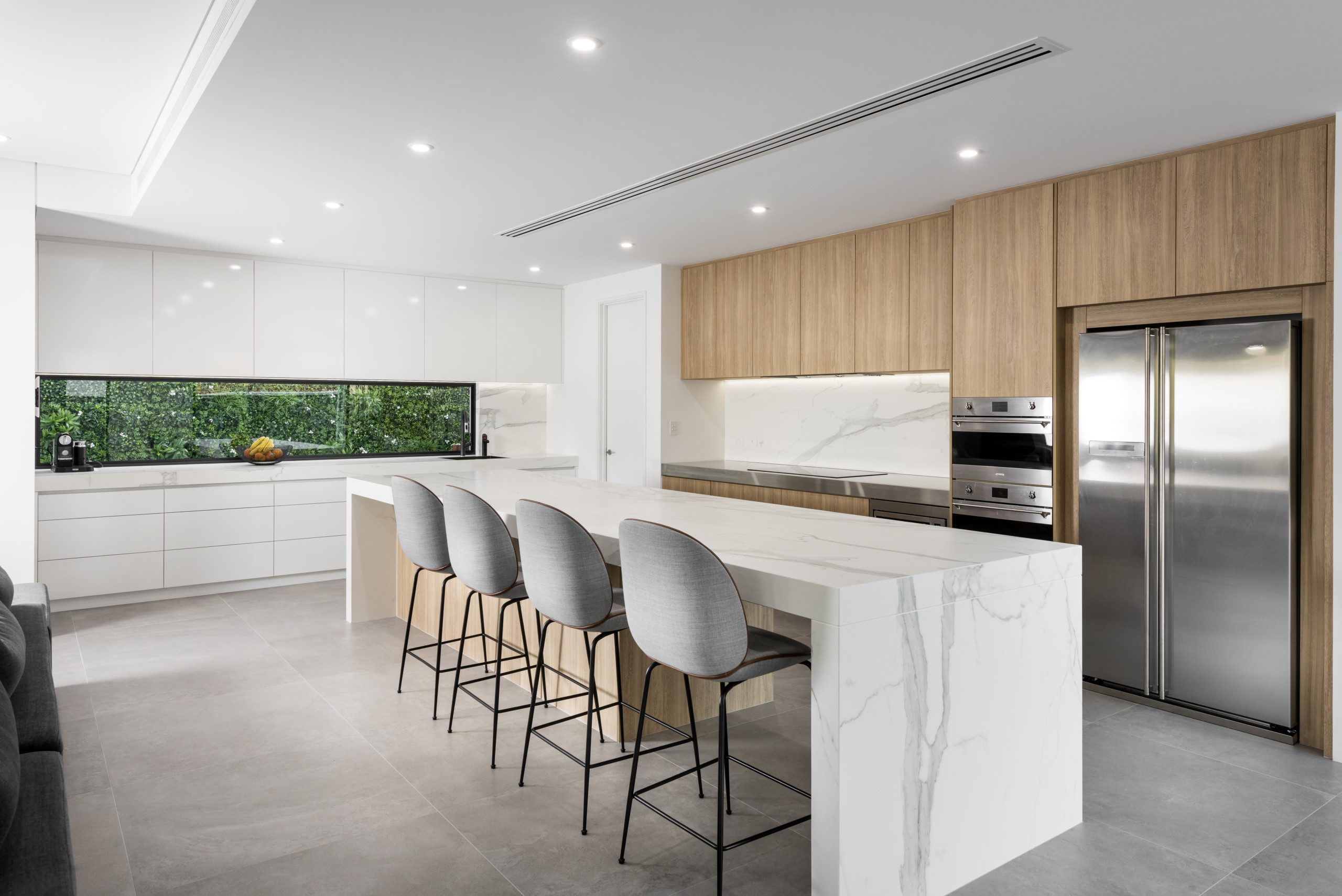 Modern looking kitchen with wood panel cabinets and marble island benchtop