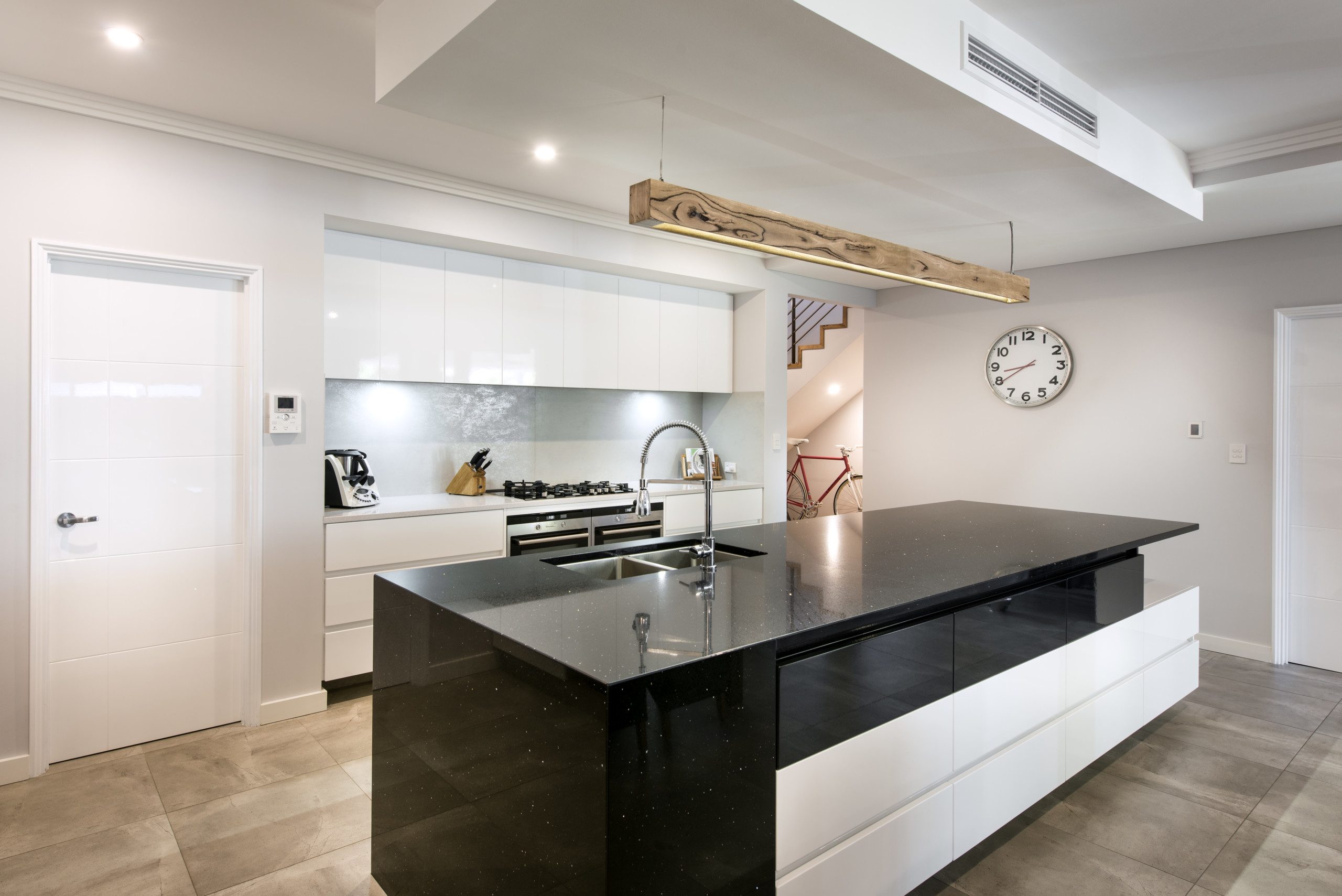 Modern kitchen with white cabinets and black stone benchtop on the island bench