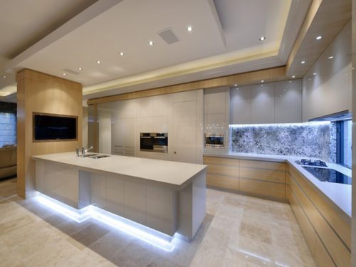 A modern kitchen with beige and brown flooring, cabinets, and island bench